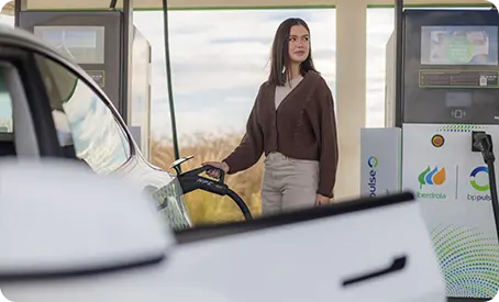 Mulher junto a carro elétrico a carregar